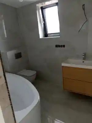 Moderne badkamer opgeleverd met marmerlook tegels en vrijstaand bad.jpg